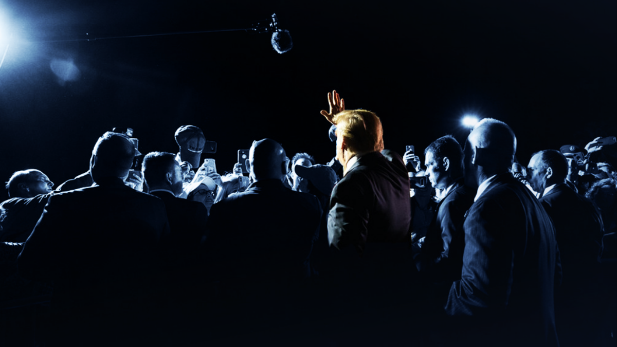 Trump from the back in a crowd of Trump supporters. Image is tinted navy except Trump.