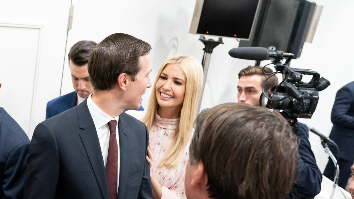 Ivanka Trump smiles at her husband Jared while near a camera and aides.
