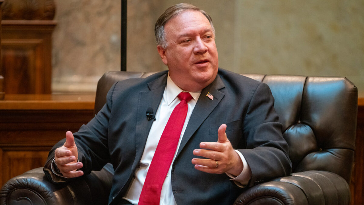 Mike Pompeo speaks emphatically while seated on a letter chair