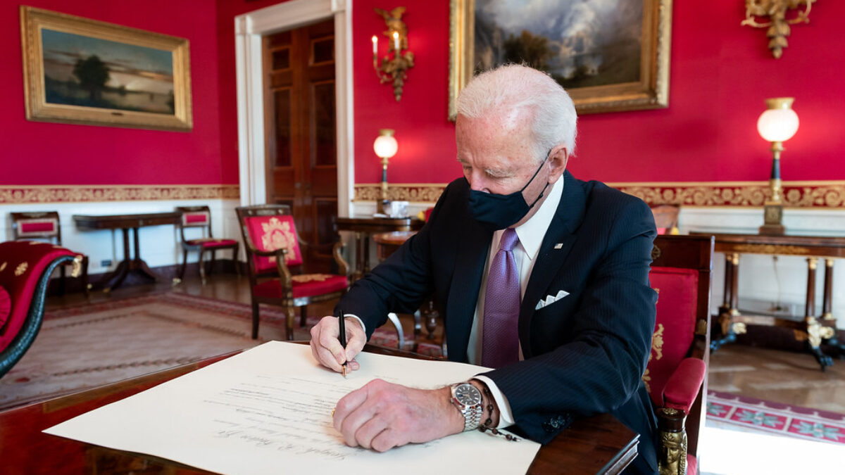 Joe Biden signs a document in the Red Room of the White House