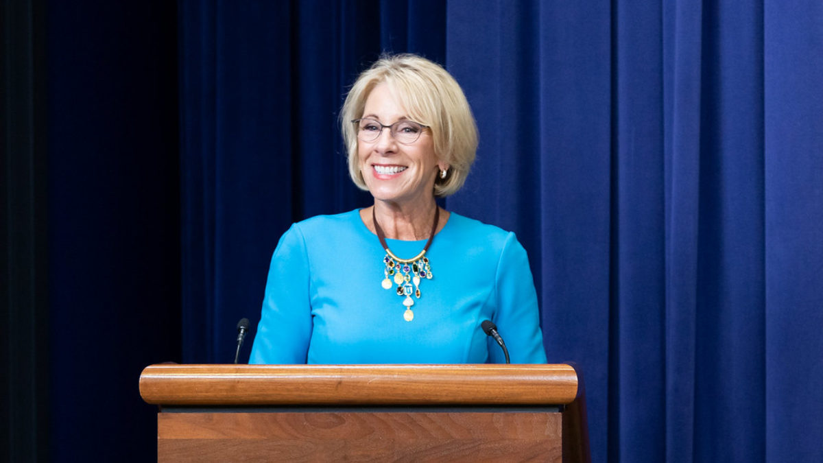 Betsy DeVos smiles while at a podium