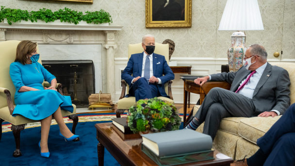Nancy Pelosi and Chuck Schumer talking with President Joe Biden, all wearing masks.