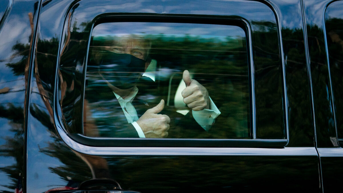 Trump with two thumbs-up in the backseat of a car