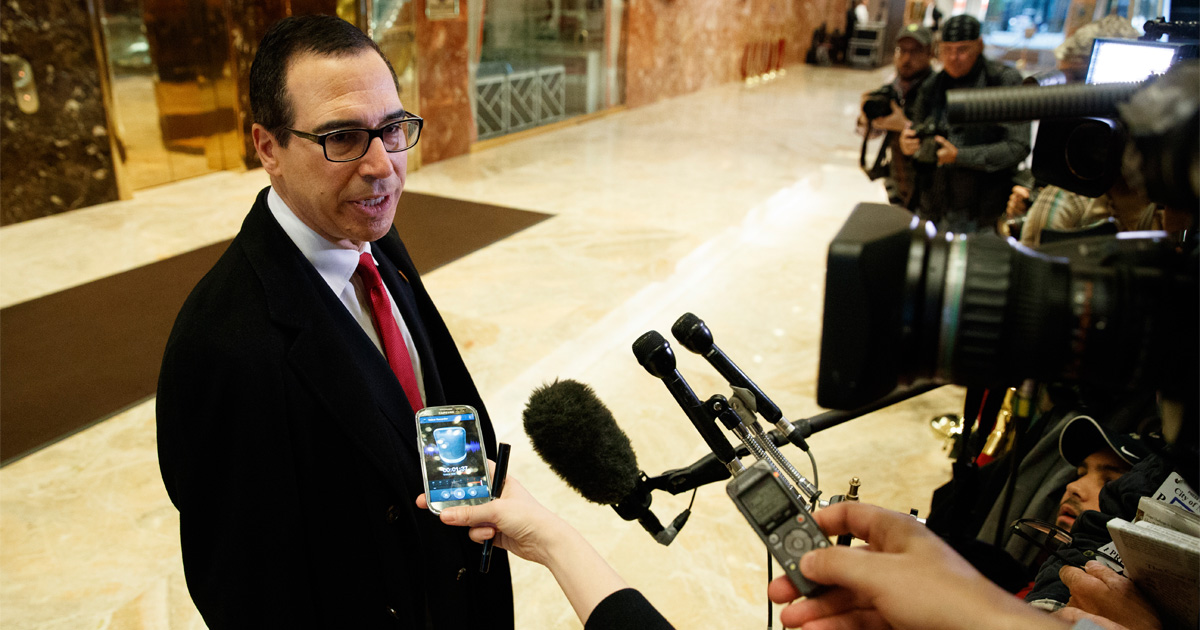 Steve Mnuchin speaks to news microphones in a hallway