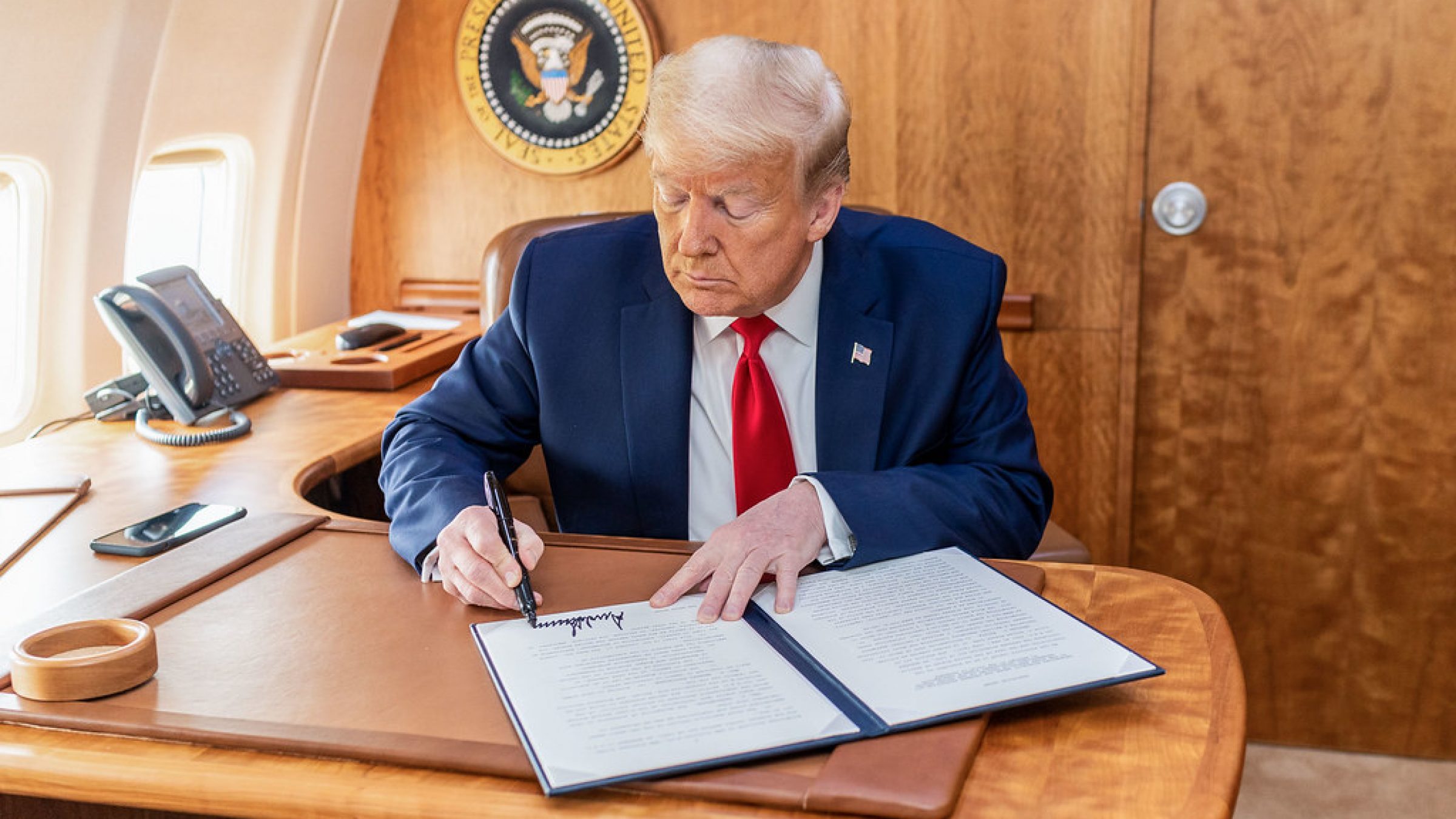 Image of President Trump at a desk, signing a bill