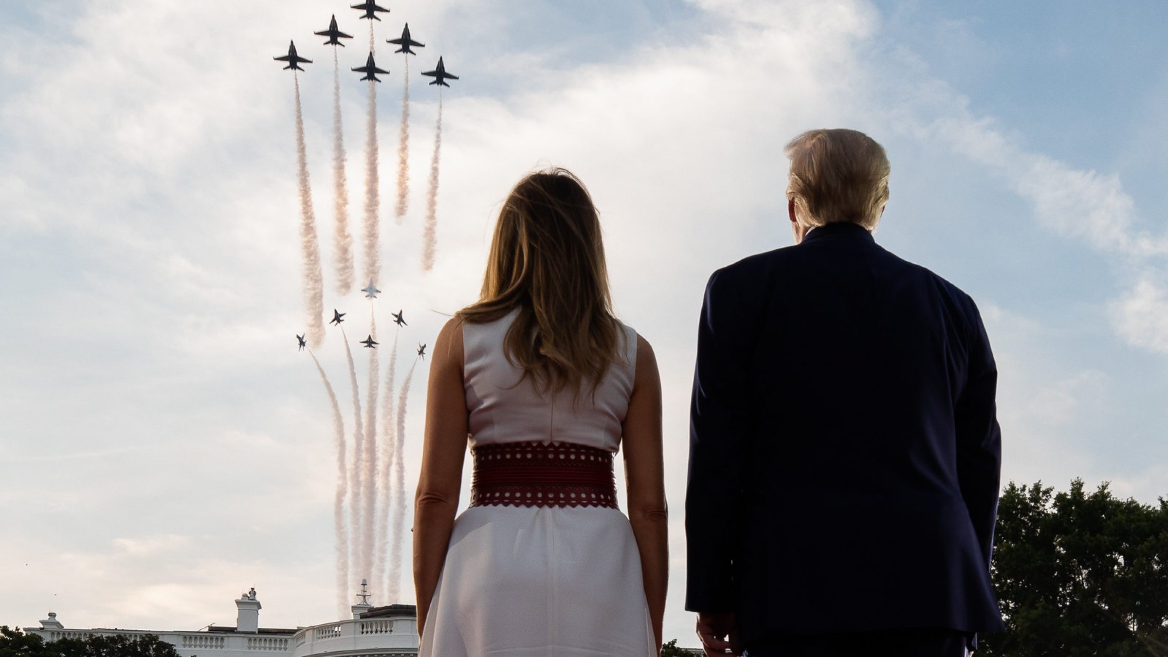 Donald and Melania Trump stand on the South Lawn of the White House, watching a military flyover